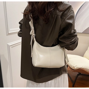 Detail of hobo bag with unique bow strap and stitching on smooth cream PU leather