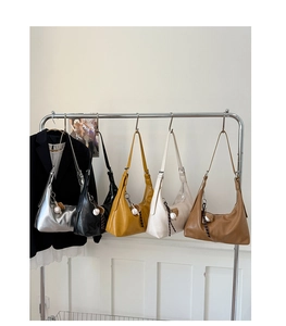 Various colors of crescent shoulder bags with baseball charms on a minimalist metal rack