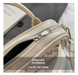 Close-up of polished silver zipper and rivet studs on beige leather square handbag