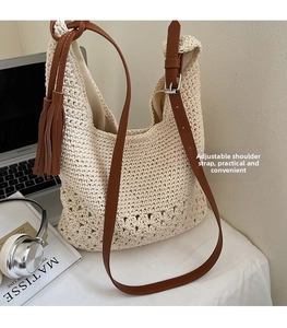 Detail of beige crochet tote with adjustable brown leather strap and side tassel accent