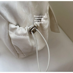 Detail of drawstring opening with metallic cord lock on a durable white shoulder bag