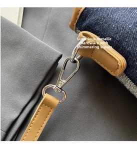 Macro detail of denim and leather bag showing silver metal hooks and premium stitching