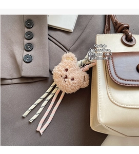 Close-up of cute plush bear charm with colorful braided tassels on a stylish beige handbag