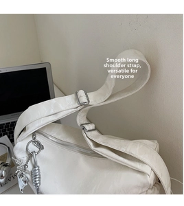 Close-up of minimalist cream white shoulder bag featuring glossy texture and silver charms