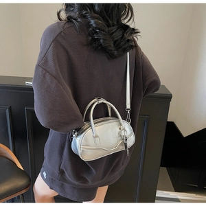 Rear view of a model wearing the silver metallic bowling bag with crossbody strap