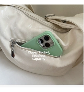 Close-up of front zipper pocket on beige crescent bag showing interior phone storage