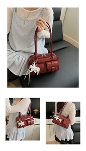 Macro detail of wine red crocodile embossed pockets and star pendant on faux leather bag