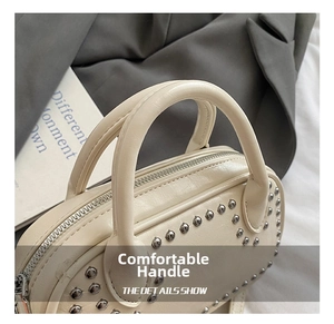 Close-up of cream-colored leather handbag featuring stylish silver metal rivet studs