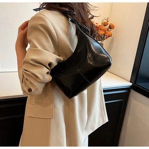 Detail of black semi-circle hobo bag featuring fine stitching on shiny leather material