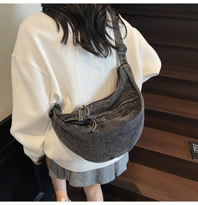 Detail view of large dark grey denim crescent bag with adjustable shoulder strap