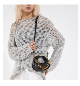 Close-up of mini black crescent moon bag with chunky gold chain on a female model