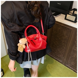 Detail of red croc-embossed handbag with a cute brown teddy bear plush pendant