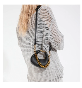 Detail of black pebbled leather crescent bag with chunky gold chain and detachable strap