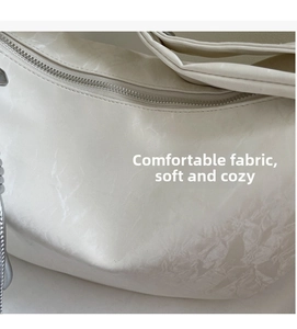 Close-up of white nylon dumpling bag showing soft cloud-textured fabric and silver zipper