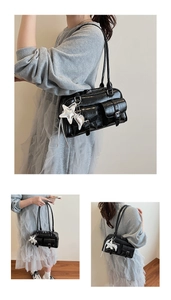 Detail of black crocodile texture shoulder bag with front buckle pockets and star pendant