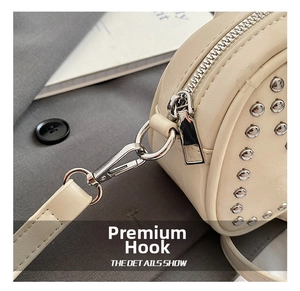 Detail shot of silver metal hook and zipper on cream rivet crossbody bag with PU texture