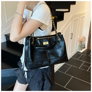 Detail of black quilted rhombus pattern bag with golden twist lock and chain strap