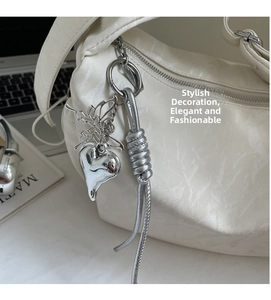 Detail of white pleated shoulder bag with silver butterfly and heart charms