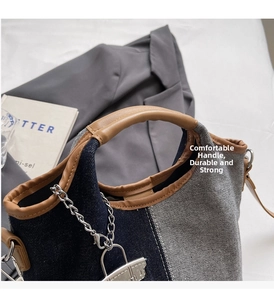 Detail of canvas bucket bag with denim contrast stitching and leather handle