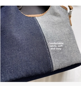 Detailed close-up of stitched denim fabric textures and brown leather trim on bag