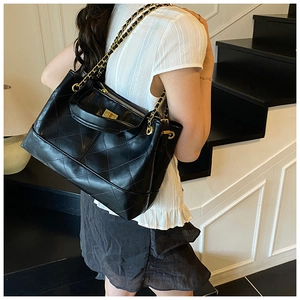 Detail of black quilted leather tote bag with gold chain strap and twist-lock clasp