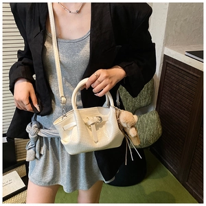 Detail shot of white crocodile pattern bucket bag with cute plush bear charm on handle