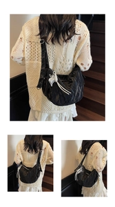 Macro view of black pleated moon bag with silver butterfly charm and white tassel detail