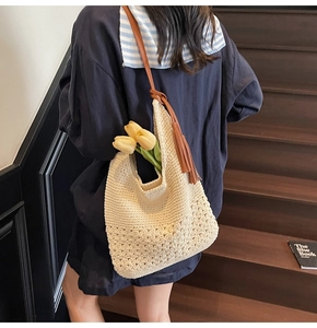 Detail of hand-woven cream tote bag featuring intricate floral crochet and leather tassels