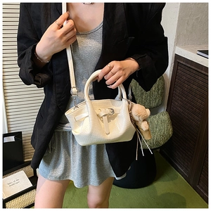 White crocodile texture handbag with plush bear charm and crossbody strap on model