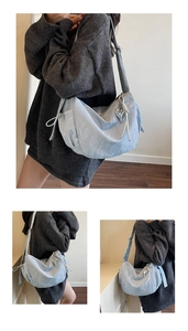 Detail of light blue crescent bag with silver heart charms and drawstring texture
