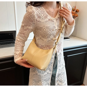 Detail of beige half-moon bag with adjustable shoulder strap and bow decoration