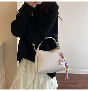 Détail du sac seau blanc crème avec pendentif arc-en-ciel et ruban sur tricot noir