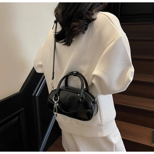 Detail of glossy black leather bowling bag with silver hardware and key charm