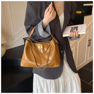Close-up of brown quilted leather handbag with gold metal lock and chain strap detail