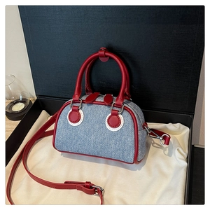 Detail of denim and red leather crossbody bag with double zippers on gift packaging