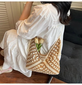 Detailed side view of large woven straw tote bag with tassels for summer beach vacation