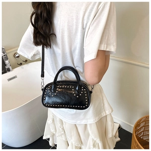 Detail of a chic black faux leather mini bowling bag with silver studs and top handles