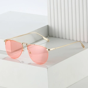 Detail of pink lens aviator sunglasses with a slim gold metal frame on a white display