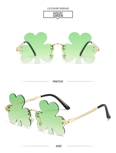 Detail view of gold metal temples and green clover-shaped rimless lenses of party sunglasses