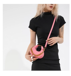 Close-up of pink mini crescent bag with lychee grain leather and gold chain detail