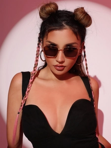 Modische quadratische Metall-Sonnenbrille mit dunklen Gläsern am Modell vor rosa Hintergrund