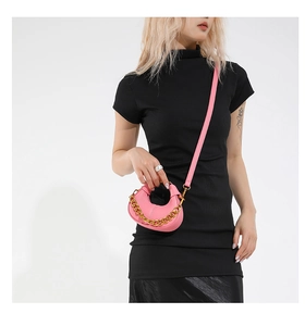 Detail of pink semi-circular crossbody bag with lychee grain and gold chain decoration