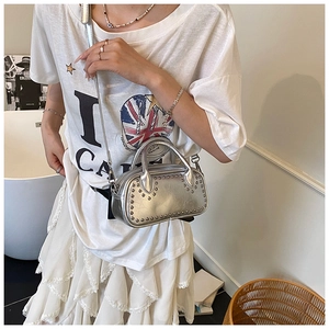 Detail of silver metallic crossbody bag with studs, shown in a lifestyle fashion setting