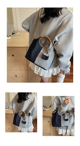 Close-up of two-tone denim bucket bag with leather handles and decorative lock charm