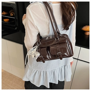 Details der dunkelbraunen, glänzenden Schultertasche mit Krokostruktur und Schnallentaschen