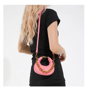 Détail du sac croissant rose avec texture litchi et chaîne dorée sur robe noire