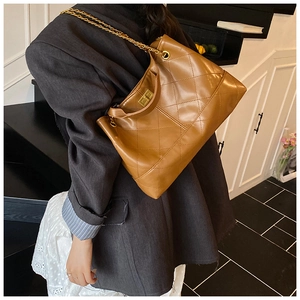 Detail of caramel brown quilted leather texture and gold chain on the shoulder bag