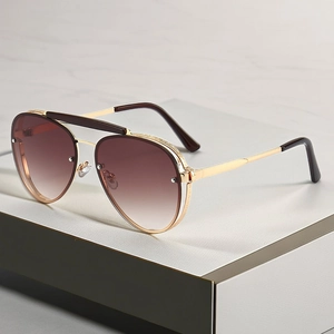 Close-up of gold metal aviator sunglasses with intricate engraved bridge and gradient lenses