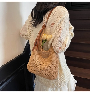 Detail of woven beach tote with intricate hollow flower pattern and leather tassel