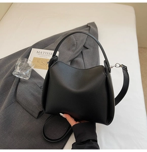 Vue détaillée du cuir noir grainé façon litchi et des finitions métalliques du sac